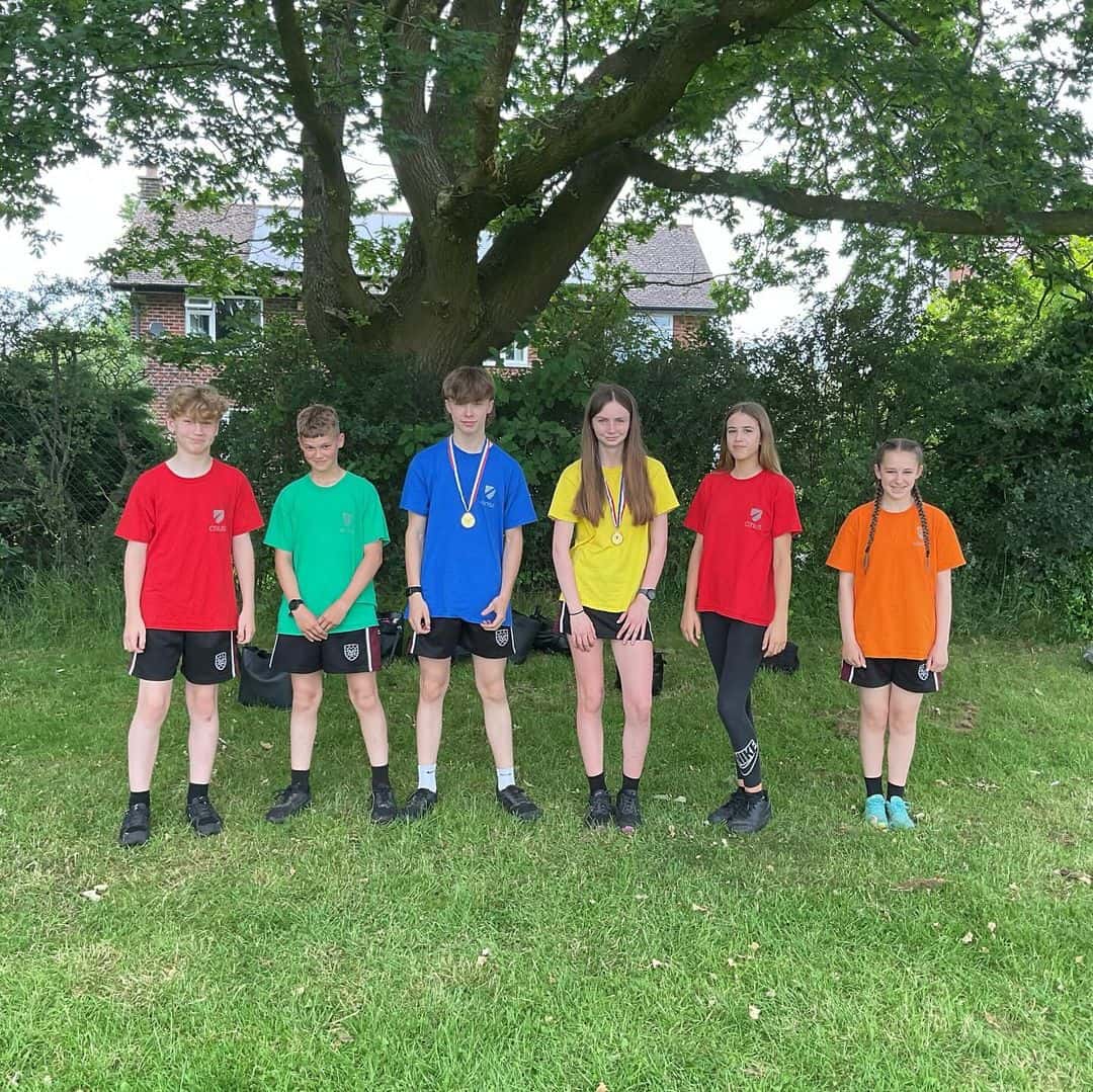 A group of students from Hazel Grove High School stand in their House colours with medals from winning their events in Sports Day.