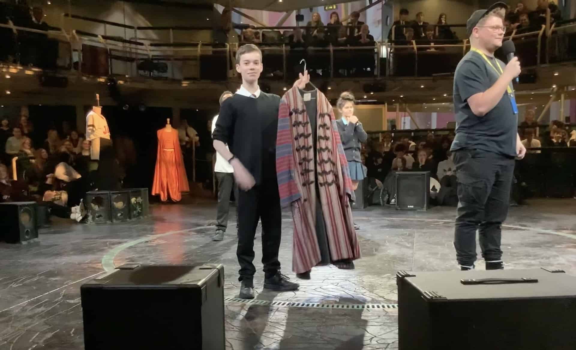 AC costume - Hazel Grove High School A student from Hazel Grove High School stands on the stage holding a Romeo costume at the Royal Exchange Theatre.