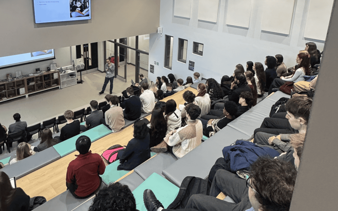 View of the back of students sat in an auditorium listening to a talk.